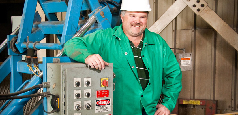 construction man with a green jacket leaning against a control panel