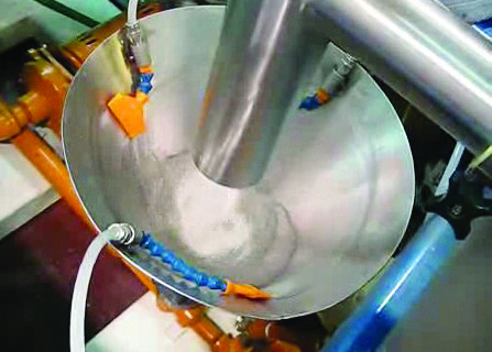 the inside of a Liquid/solid systems. Metal tube pouring a white powder in to a industrial looking bowl