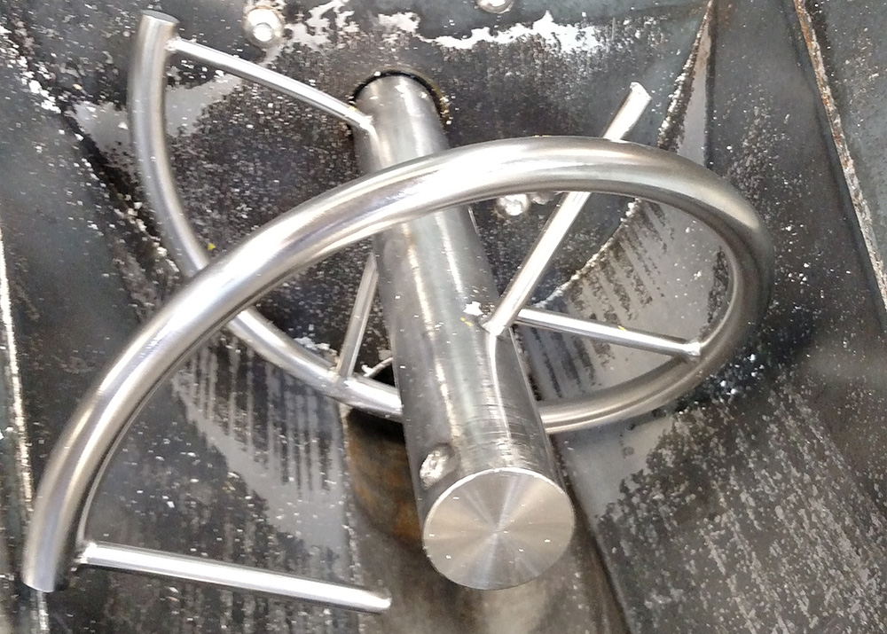 Stainless steel industrial mixing auger inside a metal hopper.