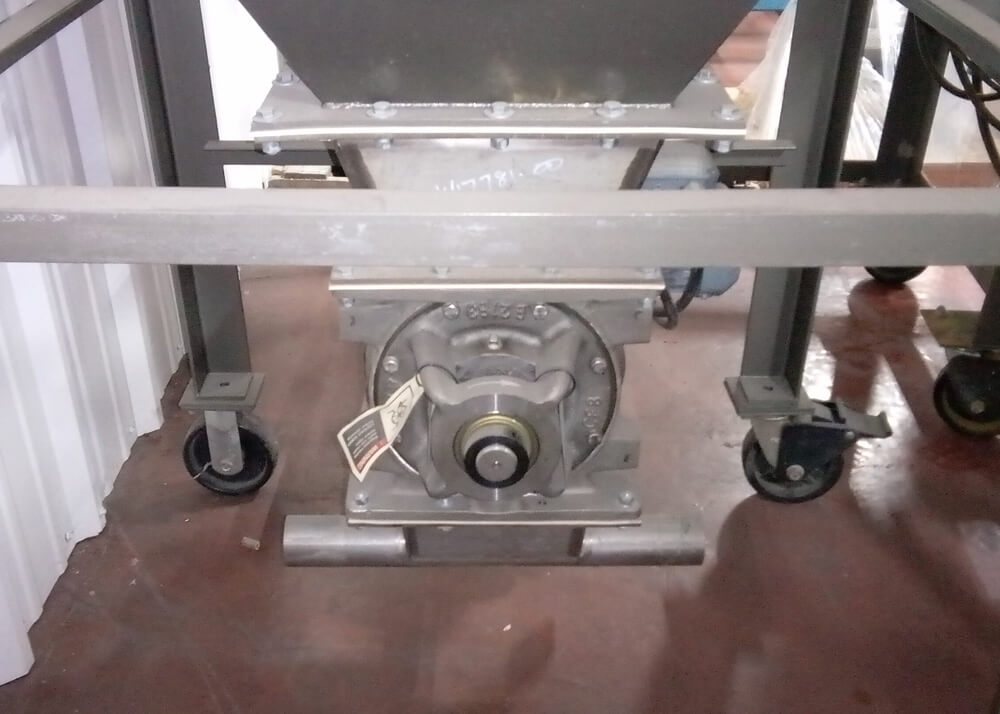 Industrial metal hopper assembly on wheels with a central circular rotating component and an attached identification tag.