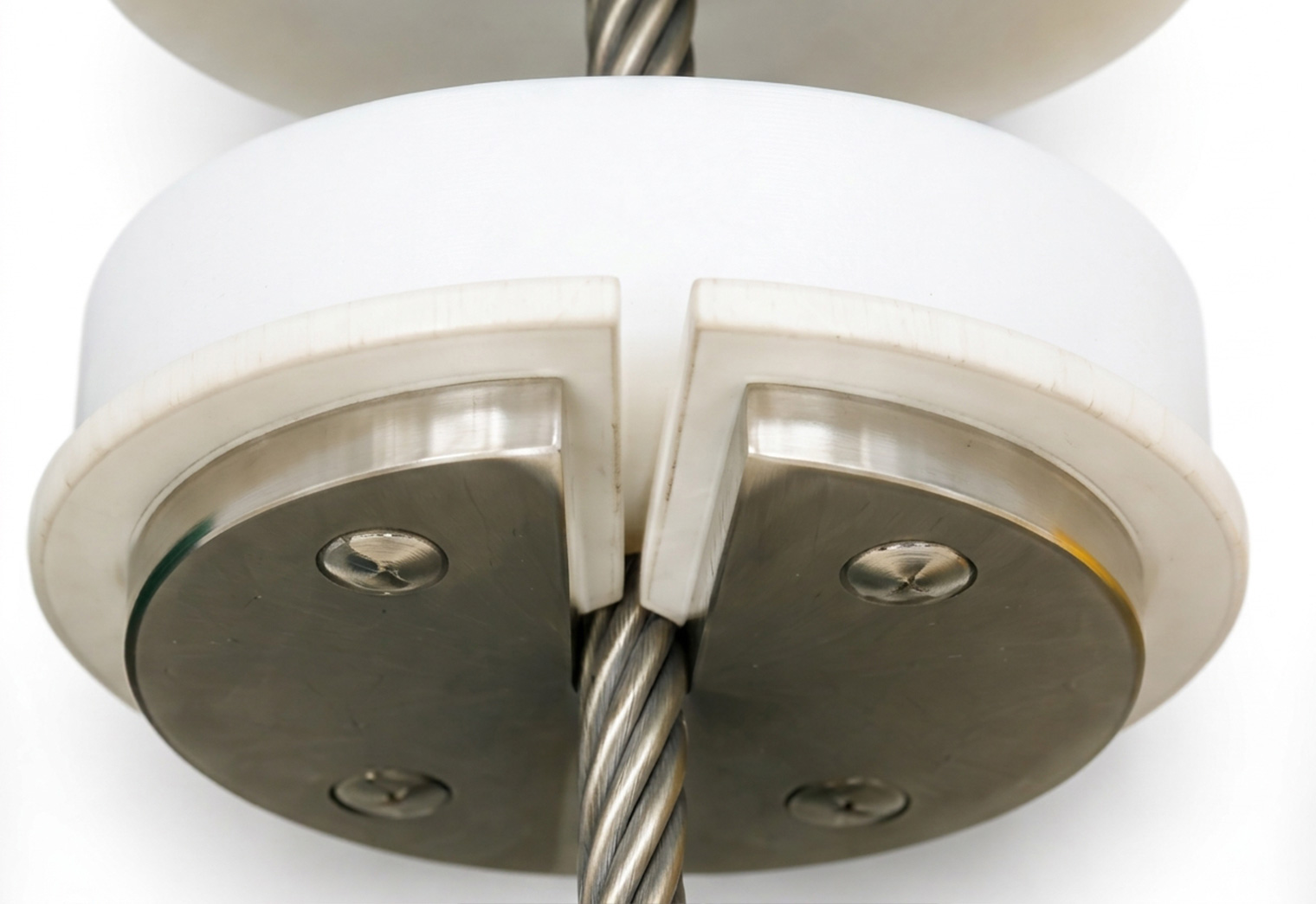 A close-up view of a metal cable passing through a white circular fixture with metal plates secured by screws.