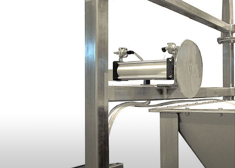 A pneumatic cylinder mounted on a metal frame above a hopper.